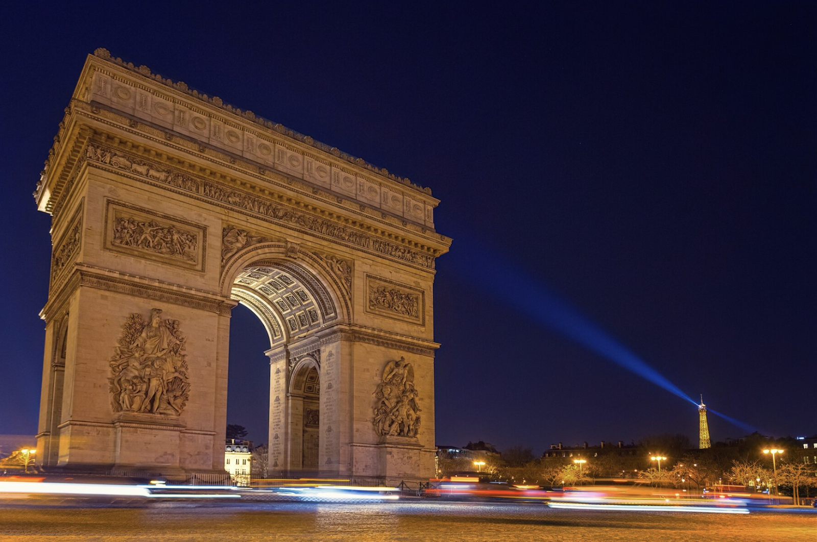 The Arc de Triomphe and the Eiffel Tower illuminated during a nighttime electric bike tour of Paris.