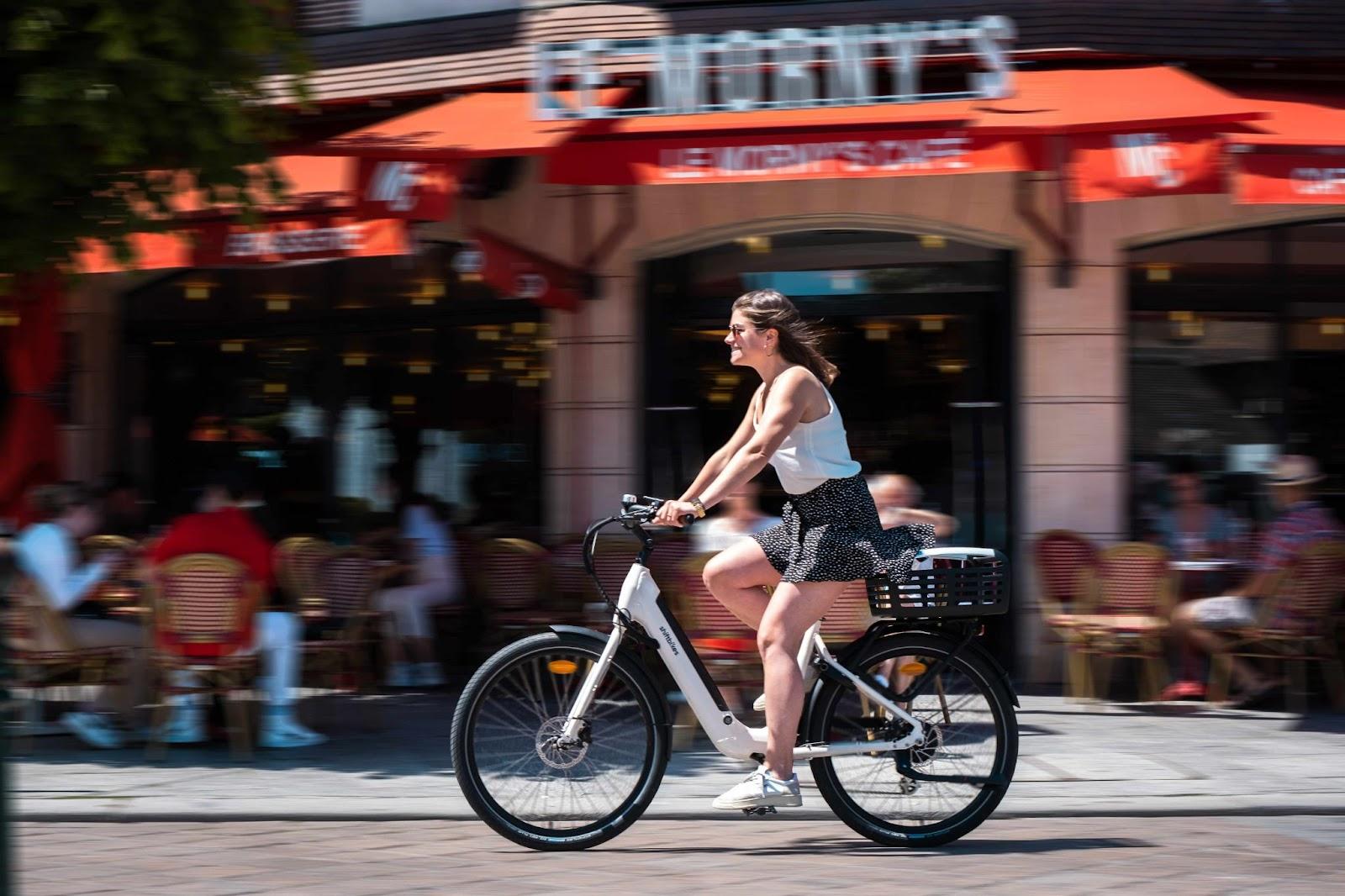 Une jeune fille en vélo qui roule dans les rues de Paris