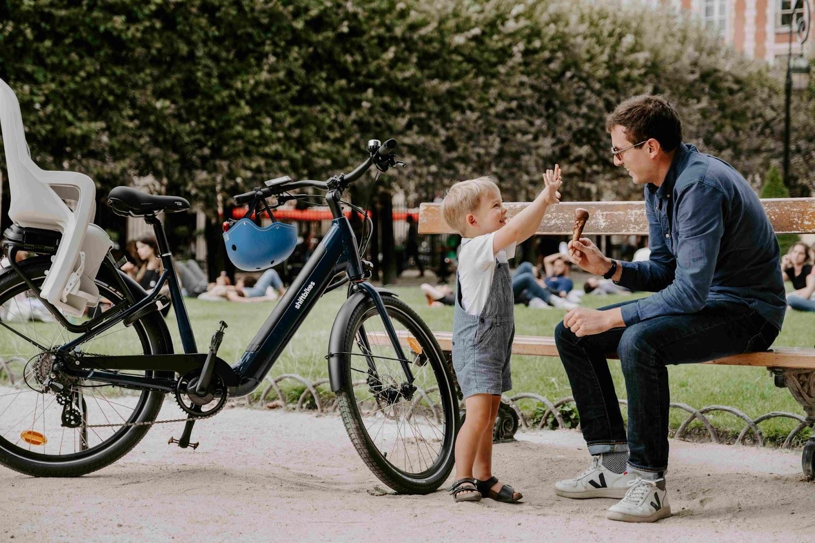 A family on electric bikes taking a break in a park in Paris