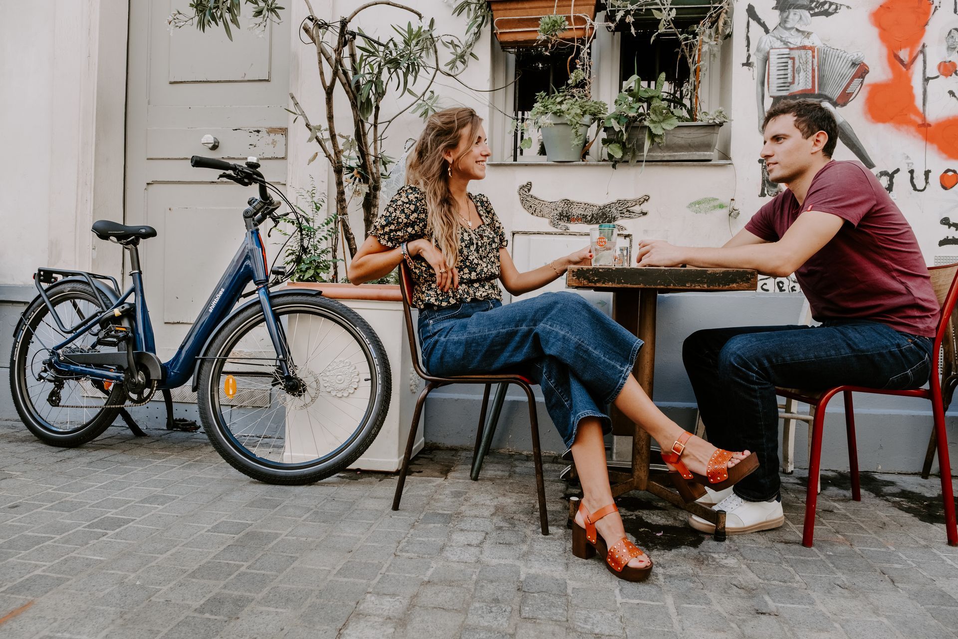 un couple assis à une terasse en extérieur à paris près de leurs vélos de location
