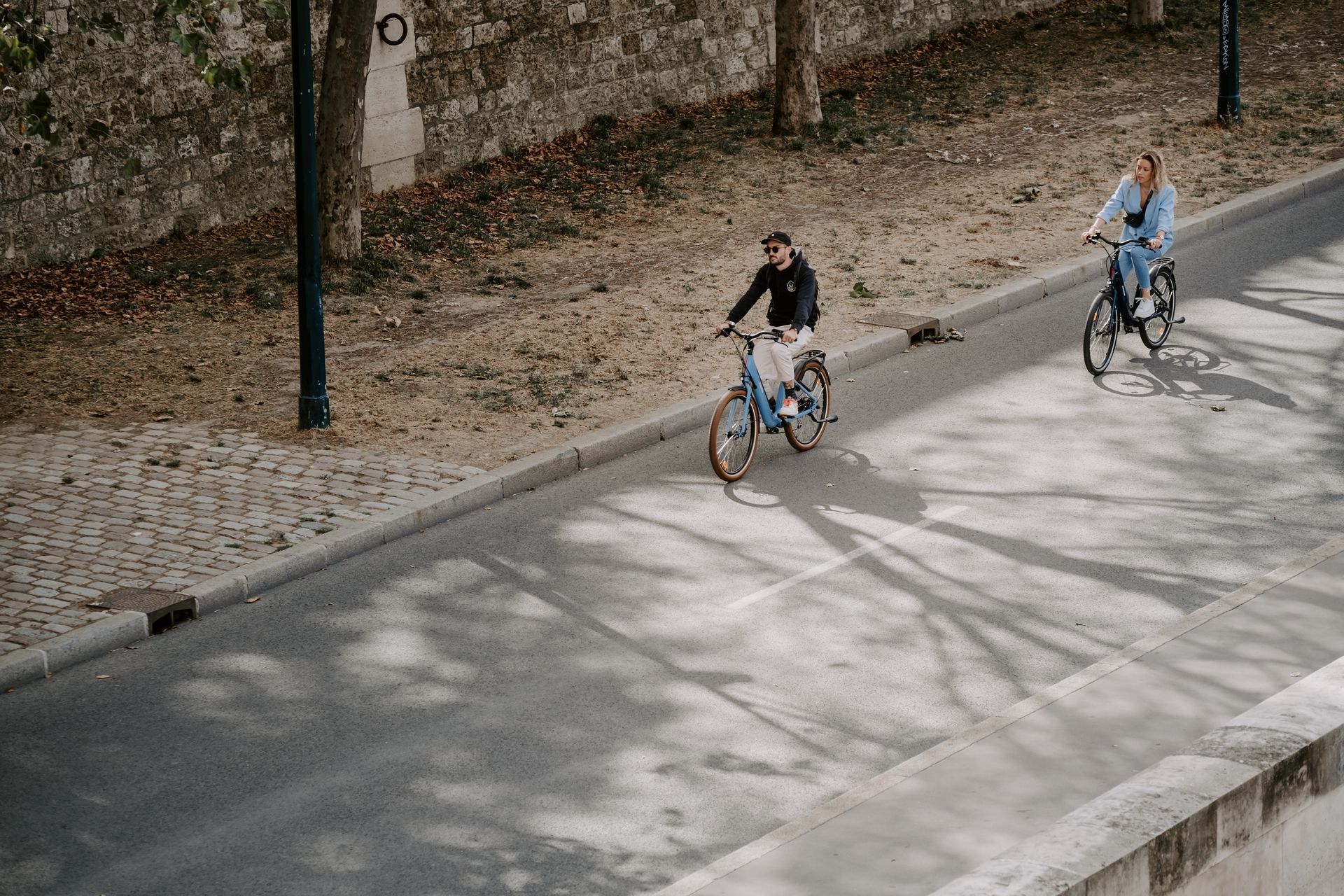 un homme suivi d'une femme, les deux à vélo