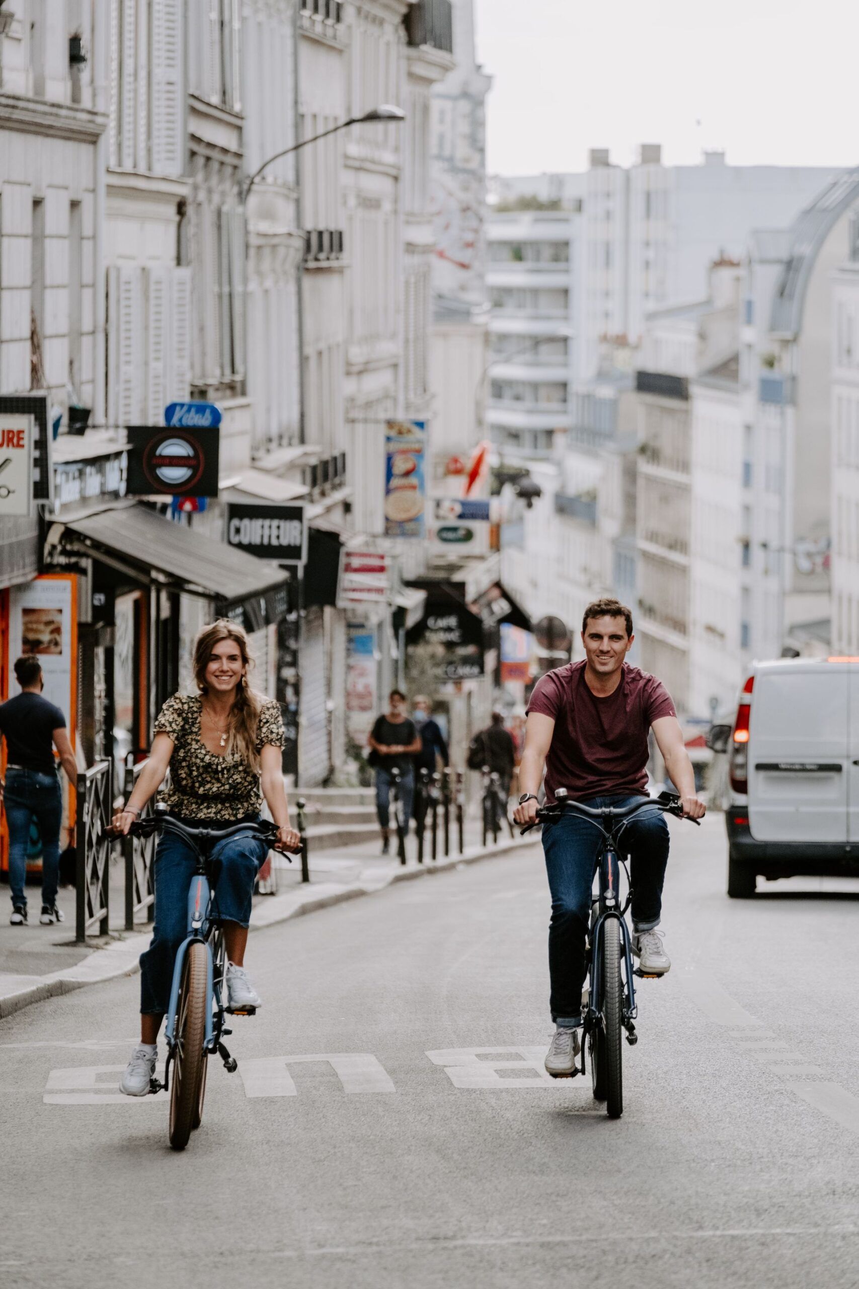 un jeune couple à vélo dans une rue parisienne en montée