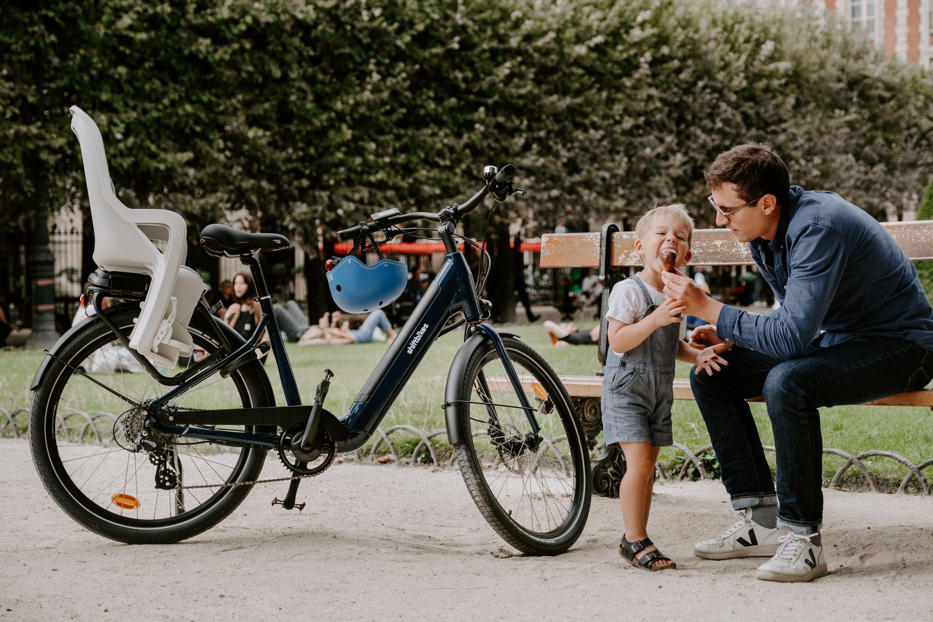 un père et son jeune enfant dans un parc à côté du vélo avec siège enfant