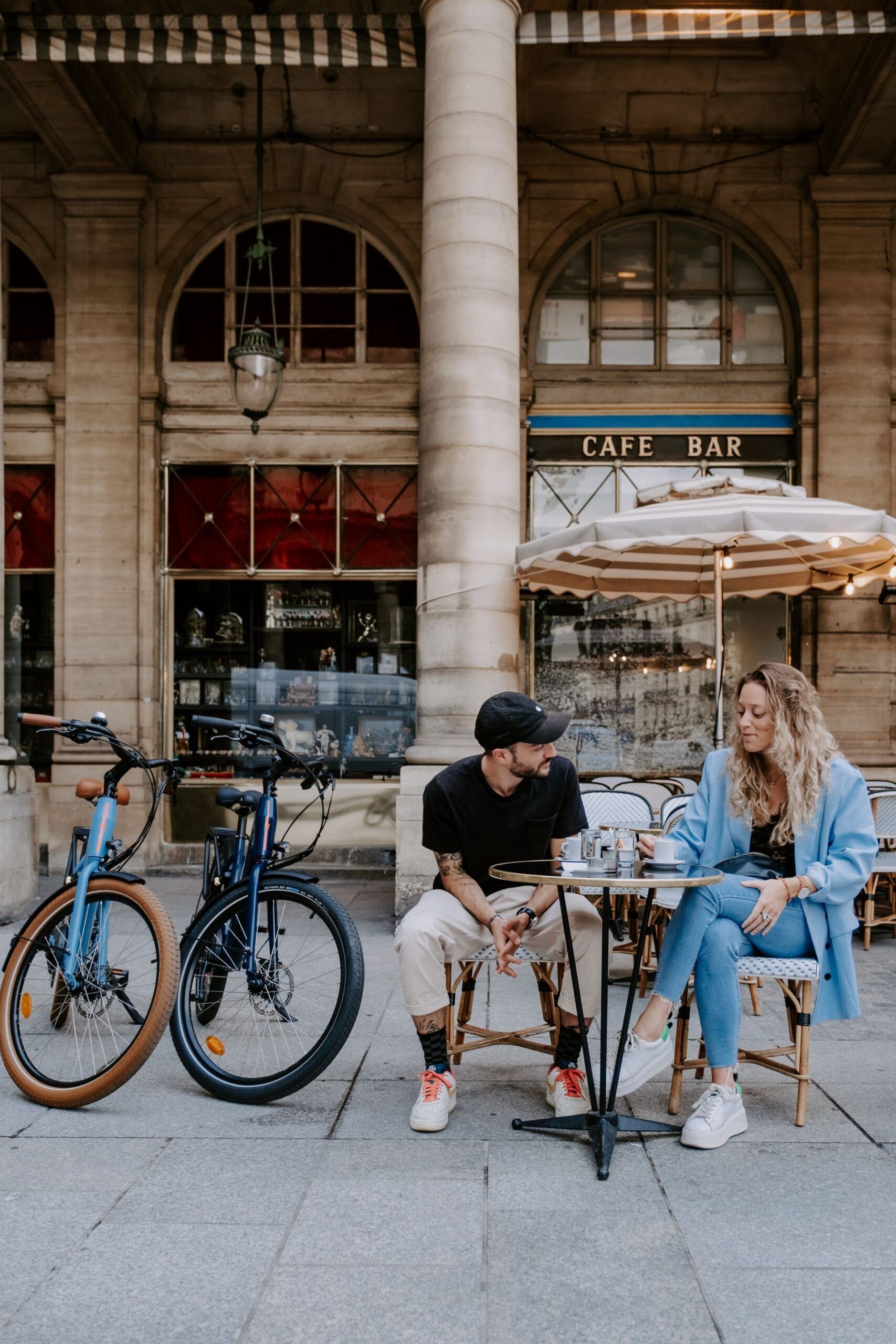 une femme et un homme à vélo se sont arrêtés pour boire un café à une terasse