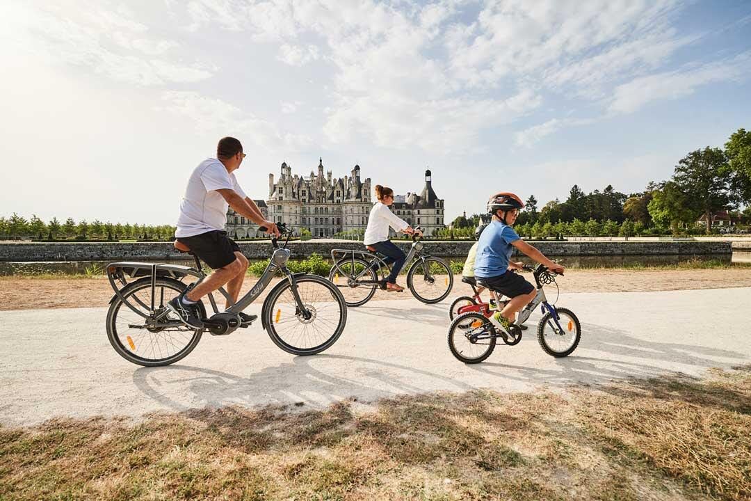 Une famille visitant le château de Chambord à vélo électrique